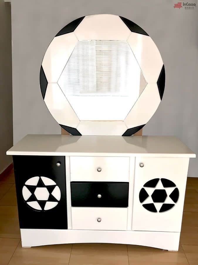 Se presenta el tocador blanco con detalles negros y espejo redondo decorado como balón de fútbol. Incluye dos puertas laterales con diseño deportivo y tres cajones centrales, combinando almacenamiento funcional y temática futbolera ideal para habitaciones juveniles.
