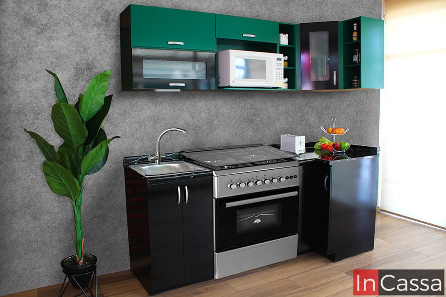 Cocina en escuadra de 2.10m x 80cm diseñada para estufa. La cocina consta de dos módulos superiores de color verde y dos módulos inferiores de color negro, estos últimos además cuenta con cubierta de formaica en estilo de mármol negro, mientras que la alacena superior cuenta con espacio para microondas.