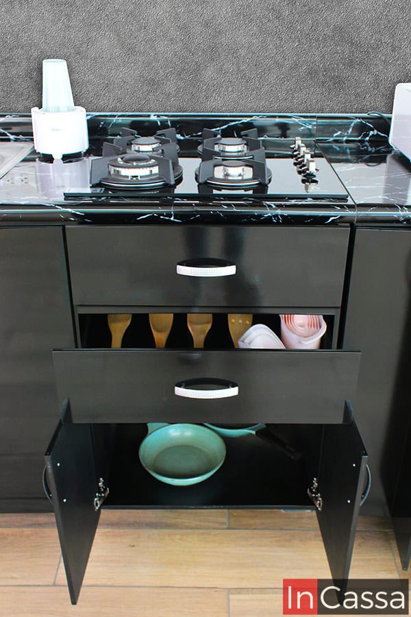 La imagen destaca los compartimentos centrales del módulo inferior negro de la cocina, entre los que se encuentran un cajón y un compartimento inferior, ambos con suficiente espacio para guardar utensilios de cocina; mientras que en la parte superior se encuentra un cajón falso, el cuál oculta la instalación de la tarja empotrable.