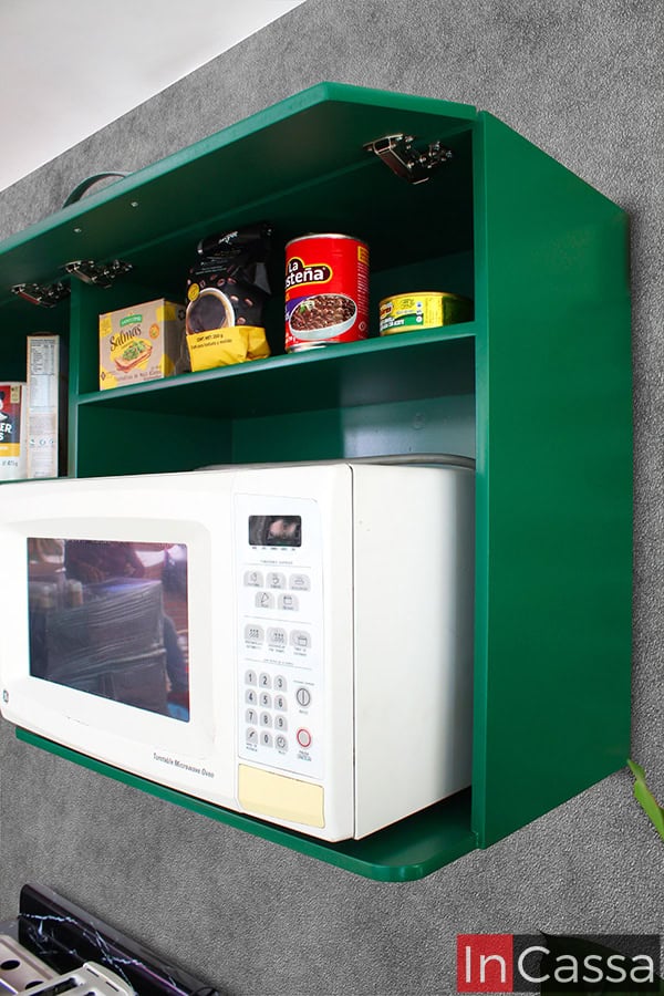 Imagen desde una toma lateral de la alacena superior de la cocina, la cual destaca el espacio para microondas y uno de los compartimentos del módulo. La totalidad del módulo mantiene el mismo tono verde tanto en su estructura externa con en la interna.