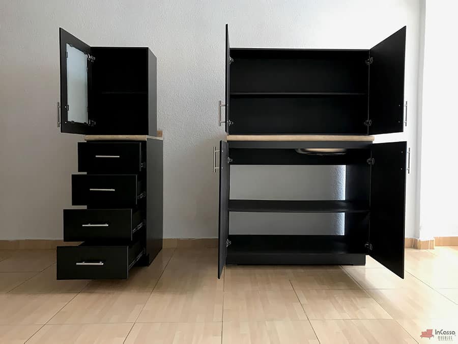 En esta imagen se presenta un conjunto de módulos de cocina en acabado chocolate mate, con gabinetes superiores e inferiores abiertos que muestran un amplio espacio de almacenamiento. El módulo lateral cuenta con cajones deslizantes y una alacena con puerta de cristal esmerilado, mientras que el otro módulo ofrece estanterías interiores con puertas de apertura lateral, ideal para optimizar el orden en la cocina.