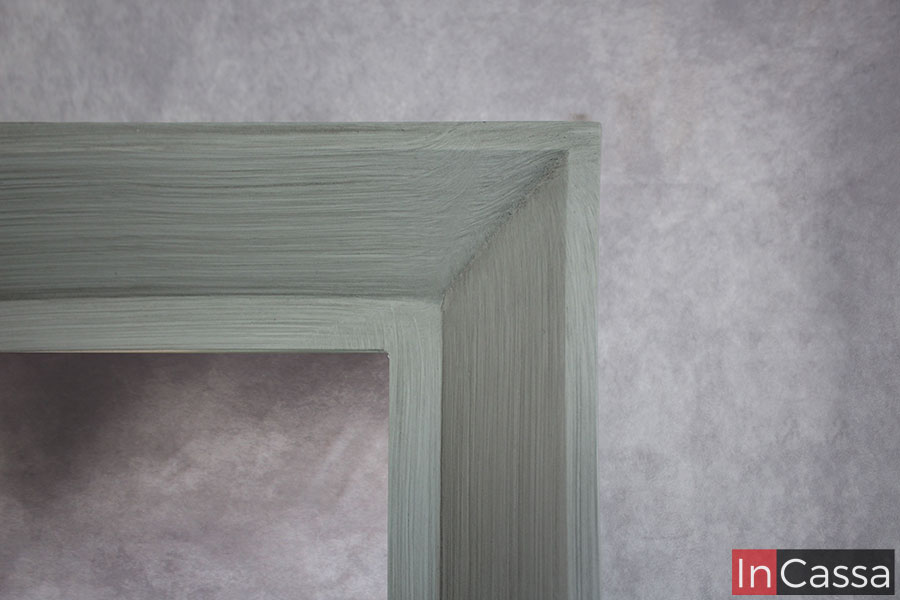 La toma da un enfoque cercano al marco del espejo incluido en el tocador destacando el acabado laqueado en la pintura gris cenizo claro así como los detalles de su diseño.