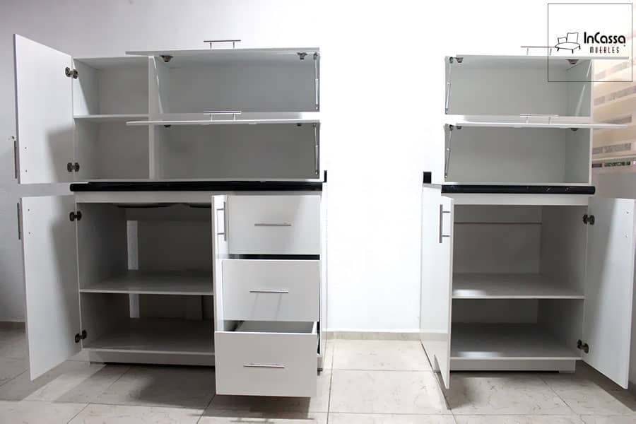 La foto muestra los módulos de almacenamiento de la cocina integral blanca con puertas y cajones abiertos. Cuenta con alacenas superiores abatibles con pistón a gas, cajones espaciosos y gabinetes inferiores con estantes amplios, maximizando la organización y funcionalidad del espacio.