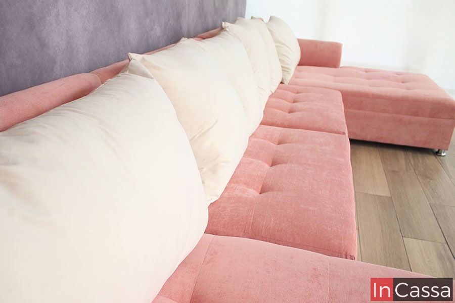 En esta foto lateral de la sala, podemos ver con mayor cercanía los seis cojines en suede hueso que incluye la sala, así como una mejor vista de los asientos en suede rosa.