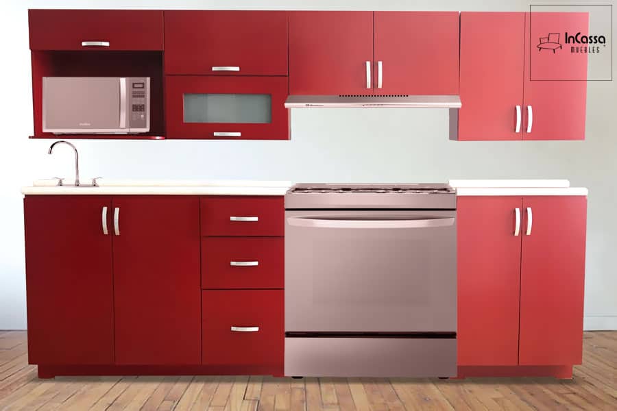 La imagen presenta una vista frontal de la Cocina Integral TORONTO para Estufa en acabado rojo quemado. Se aprecian módulos superiores e inferiores, espacio para microondas, estufa y tarja. Destacan sus jaladeras metálicas curvas y la cubierta de formaica blanco fresh que realza el contraste.