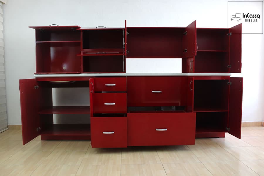 Se nos muestra la cocina en una presentación con todos sus compartimentos abiertos dejando a la vista sus interiores, los cuales conservan el mismo color borgoña que puede apreciarse en la estructura externa del mueble.