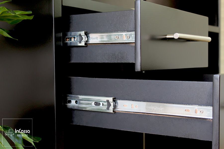 La foto muestra en primer plano los detalles de los cajones del módulo izquierdo del esquinero, fabricados en tono chocolate mate con jaladeras cilíndricas metálicas. Se aprecian las correderas de extensión, que permiten un deslizamiento suave y seguro.