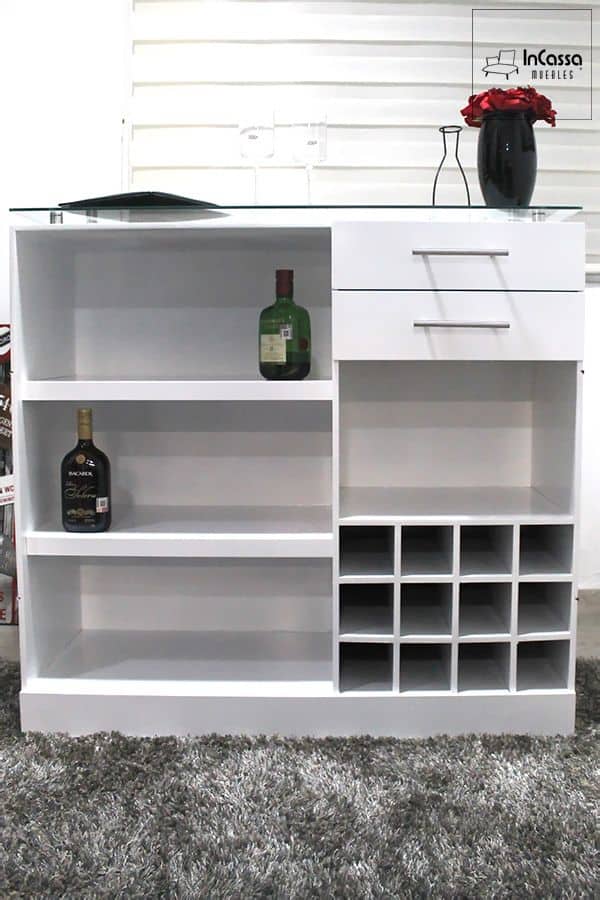 La imagen muestra la parte posterior de la Cantina Modelo UGANDA en color blanco, con cava para botellas, amplio espacio para copas y accesorios, y dos cajones con jaladeras metálicas. Su cubierta de cristal templado añade elegancia y modernidad al diseño funcional del mueble.