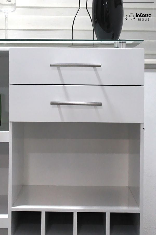 La foto presenta una vista cercana del área superior de la Cantina Modelo UGANDA en color blanco, destacando sus dos cajones amplios con jaladeras metálicas y su cubierta de cristal templado. El diseño combina líneas limpias y acabados brillantes, ideal para ambientes modernos y elegantes.