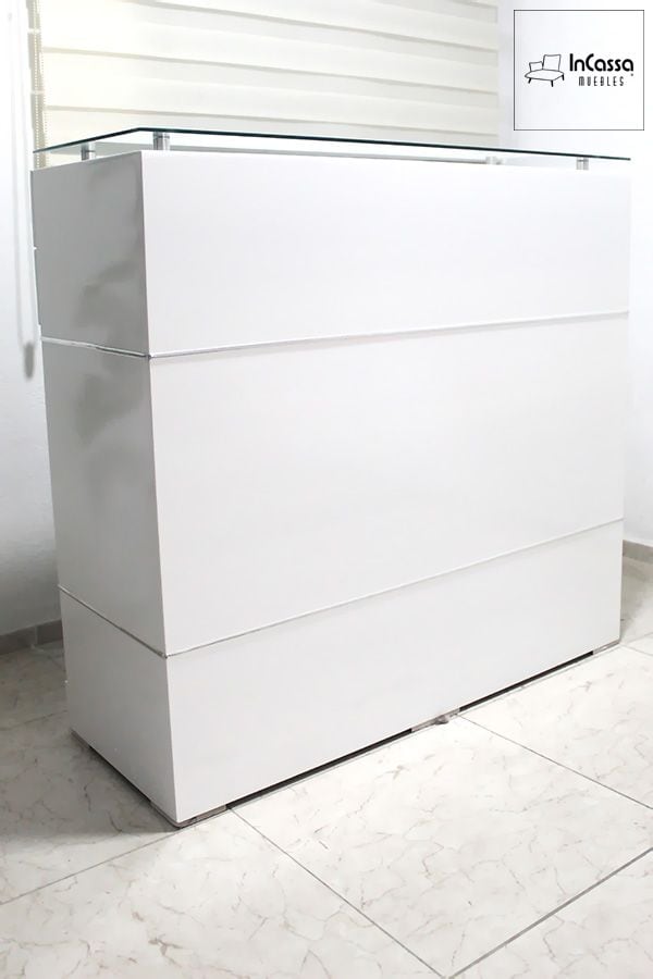 La fotografía muestra una vista en ángulo de la Cantina Modelo UGANDA en color blanco, donde se aprecia su elegante cubierta de cristal templado y su estructura de líneas minimalistas. El acabado brillante realza la luz del entorno, aportando un toque moderno y sofisticado al espacio.