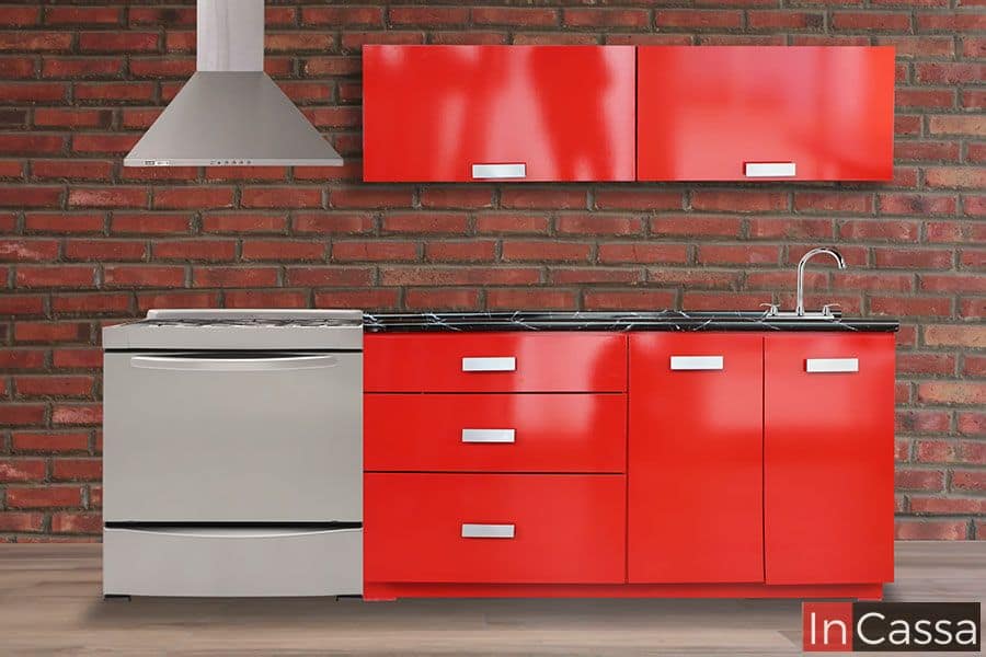 Una toma frontal muestra la cocina Venezuela en acabado rojo vivo brillante, con cubierta de formaica tipo mármol negro, tarja metálica y alacenas superiores horizontales. Su diseño moderno destaca frente al fondo de ladrillo expuesto.