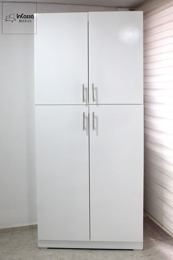 La foto presenta la alacena con diseño minimalista y acabado blanco brillante desde una toma frontal. Sus cuatro puertas con tiradores metálicos ofrecen un almacenamiento amplio y ordenado