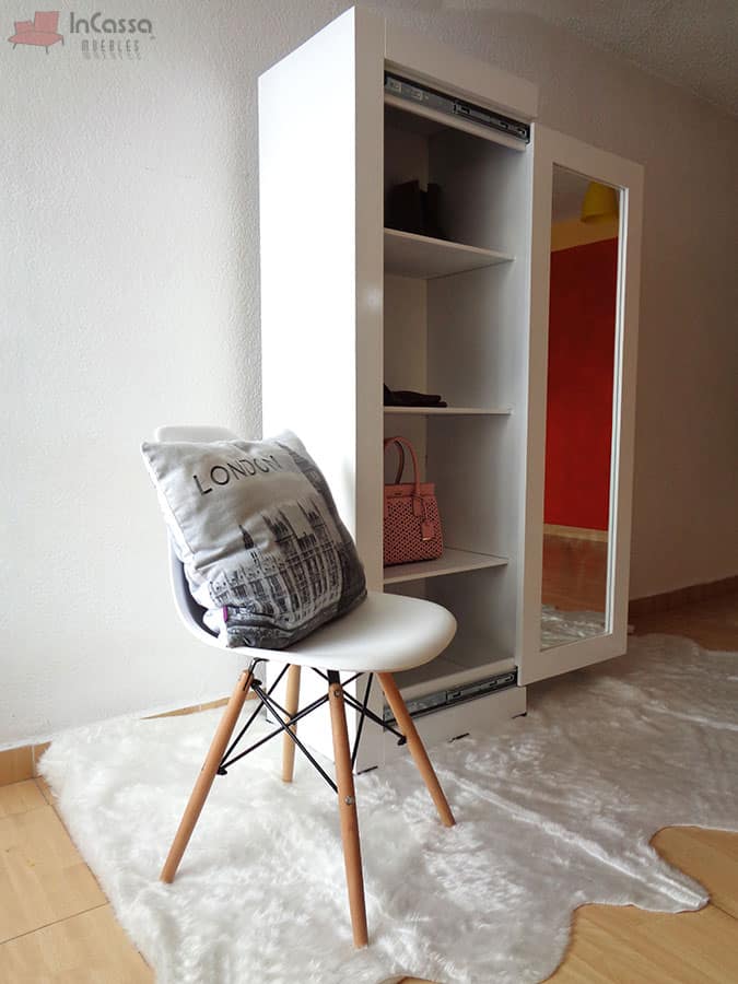 La foto presenta el armario zapatero con su puerta corrediza parcialmente abierta, revelando su interior espacioso con estantes ajustables, ideales para mantener organizados zapatos y accesorios. El acabado blanco impecable y el espejo en la puerta fusionan estilo y practicidad, adaptándose a cualquier decoración moderna.