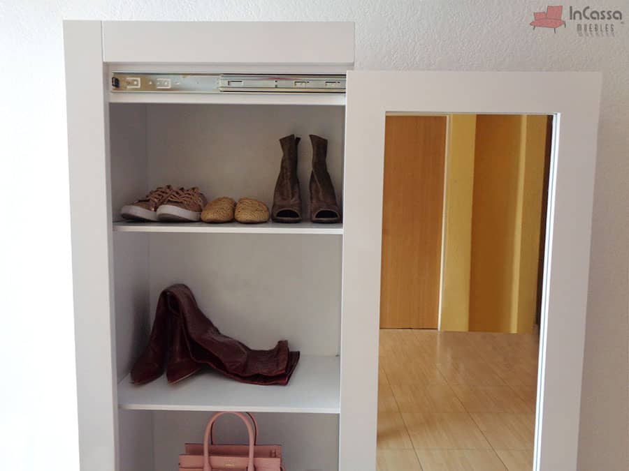 En esta toma se aprecia el interior del armario zapatero, equipado con tres amplios estantes que brindan espacio para calzado, bolsos y otros accesorios. Su diseño minimalista en blanco, combinado con el marco del espejo, añade luminosidad y elegancia al ambiente.