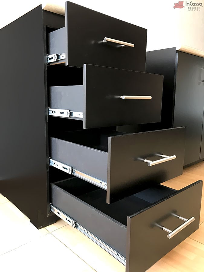 Los cajones del módulo inferior de cocina presentan una estructura robusta con correderas de metal que facilitan un deslizamiento suave. El diseño incluye jaladeras metálicas elegantes y un acabado chocolate mate, proporcionando una apariencia moderna y funcional. Los cajones ofrecen un amplio espacio de almacenamiento, ideal para utensilios y accesorios de cocina.