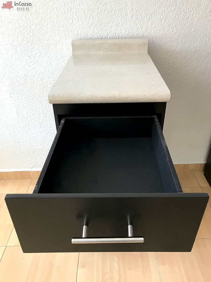 El cajón amplio del módulo inferior de cocina ofrece un generoso espacio de almacenamiento, ideal para organizar utensilios y herramientas de cocina. Presenta una jaladera metálica moderna y un acabado chocolate mate. La cubierta de formaica estilo sal y pimienta en la parte superior agrega un toque elegante y práctico, proporcionando una superficie resistente y fácil de limpiar.