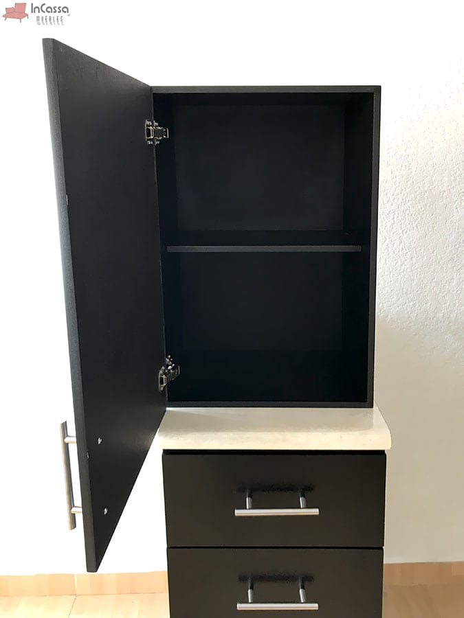 El módulo superior de puerta abatible y un estante interno, ideal para organizar utensilios de cocina. Los tiradores metálicos destacan sobre el acabado chocolate mate completo, complementando un estilo moderno y elegante.