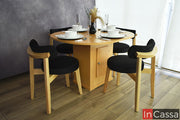 En una composición para 4 personas, el Comedor Viral en Pinterest YOKOHAMA con Mesa Ovalada presenta acabado en color natural y sillas con estructura de madera, respaldos curvos y asientos tapizados en suede negro. La mesa incorpora una base central con espacio de almacenamiento.