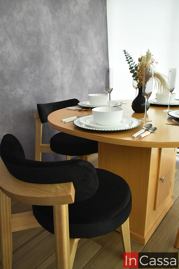En un acercamiento lateral, el Comedor Viral en Pinterest YOKOHAMA con Mesa Ovalada para 4 personas destaca su acabado en color natural y el diseño de sus sillas, con estructura de madera, respaldo curvo y asiento tapizado en suede negro. También se aprecia la base central de la mesa con compartimento.