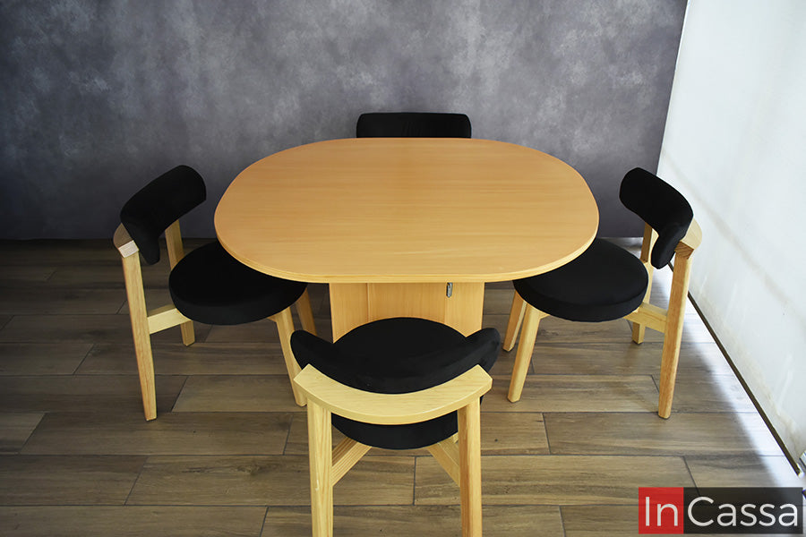 Desde una vista elevada, el Comedor Viral en Pinterest YOKOHAMA con Mesa Ovalada para 4 personas muestra la forma y amplitud de su cubierta en color natural. Las cuatro sillas se distribuyen alrededor de la mesa y presentan estructura de madera con asientos y respaldos tapizados en suede negro.