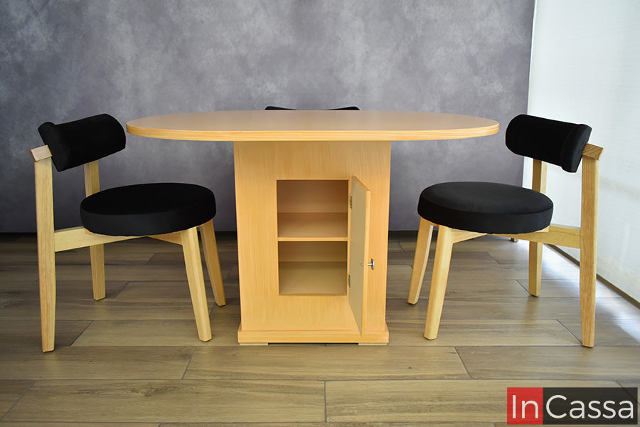 Con la puerta de la base abierta, el Comedor Viral en Pinterest YOKOHAMA con Mesa Ovalada para 4 personas permite apreciar el compartimento interior con repisa de su mesa en color natural. A los costados se observan las sillas de madera con asientos y respaldos tapizados en suede negro.