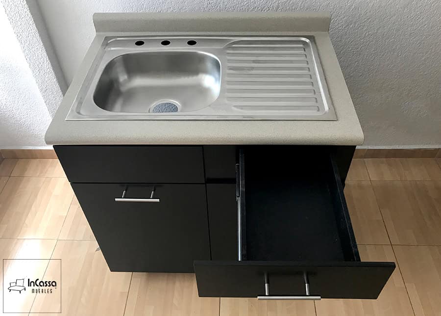 La foto presenta el módulo de tarja de la Cocina Integral ÁFRICA, equipado con una cubierta de formaica estilo granito de arena que brinda resistencia y una textura elegante. La tarja de acero inoxidable con escurridor integrado añade funcionalidad y durabilidad, mientras que los cajones y puertas con jaladeras metálicas ofrecen un almacenamiento práctico y moderno. Su diseño compacto permite un fácil acceso al área de trabajo, ideal para optimizar cocinas contemporáneas.