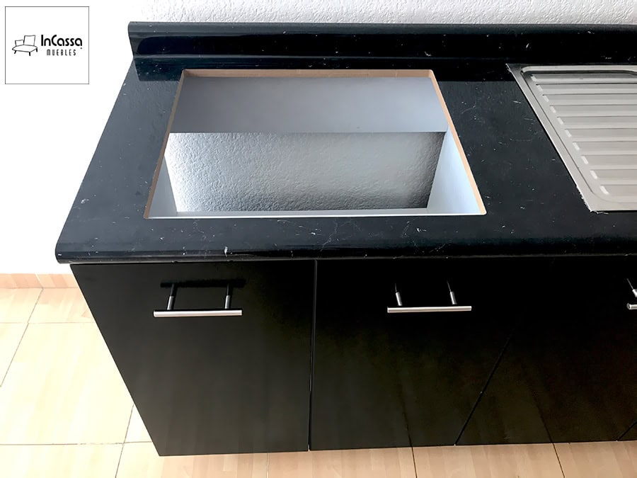 La fotografía presenta una vista superior del módulo principal de la cocina BUGA para parrilla, mostrando el espacio destinado a la tarja dentro de la cubierta de formaica estilo mármol negro. Se aprecia el contraste entre los frentes chocolate y el interior blanco del área recortada, así como la zona de escurridero a un costado, resaltando una instalación limpia y lista para equiparse.