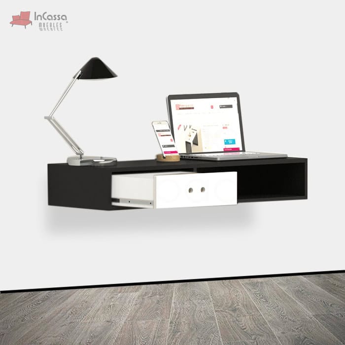 La imagen muestra un escritorio flotante en elegante color negro con cajón blanco y compartimento abierto. Su diseño minimalista ofrece un espacio funcional para laptop, lámpara y accesorios, ideal para crear un ambiente de trabajo moderno y organizado.