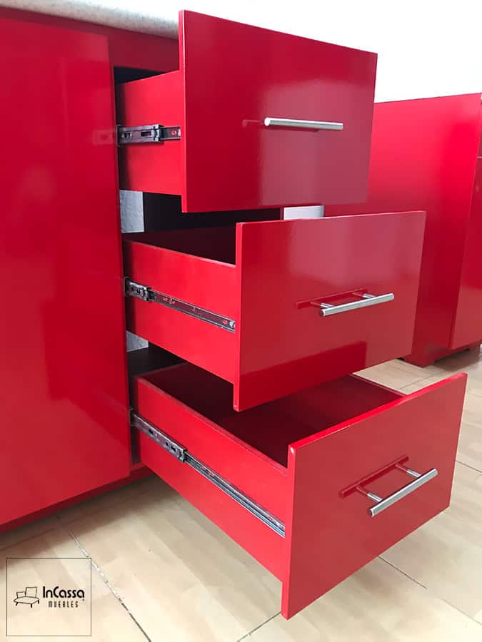 La imagen muestra los cajones del módulo inferior de la Cocina Finlandia en color rojo vivo, abiertos para destacar su sistema corredizo metálico de extensión y tiradores modernos bajo cubierta de formaica blanco fresh.