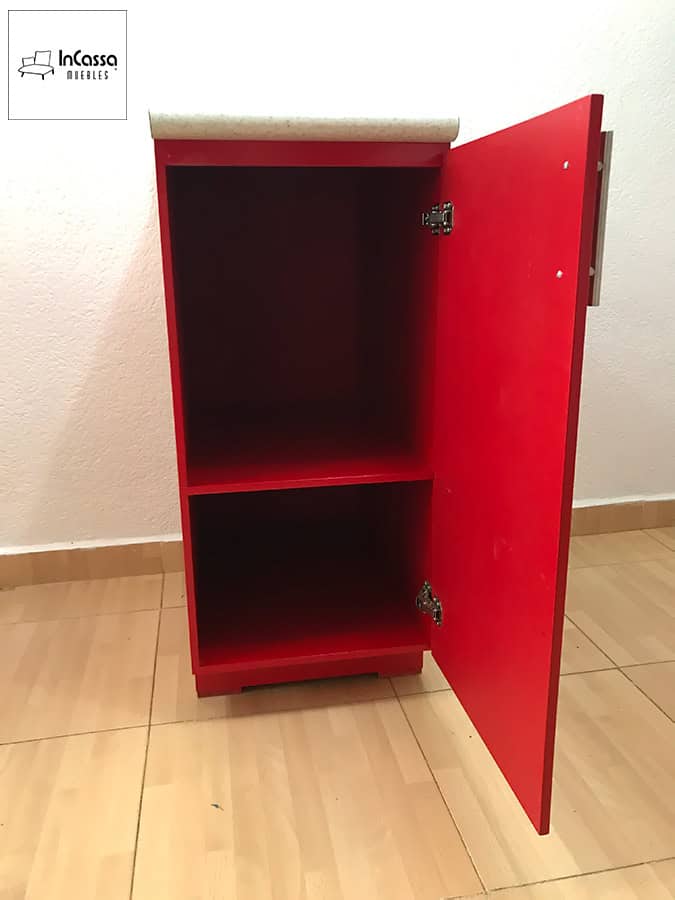 Una fotografía del módulo lateral de la Cocina Finlandia para Estufa en color rojo vivo, con puerta abierta que deja ver dos amplios compartimentos internos, todo bajo la cubierta de formaica blanco fresh que aporta contraste elegante.