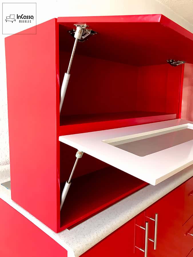 Una toma de la Cocina Finlandia en rojo vivo que resalta el módulo superior con pistón neumático y puerta blanca con vidrio, mostrando la practicidad y modernidad sobre la cubierta blanco fresh.