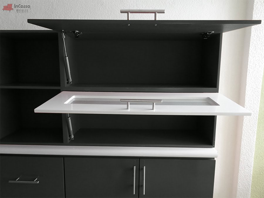 La foto presenta la alacena superior de la Cocina Integral Irlanda para Estufa en negro brillante, equipada con puerta abatible blanca con vidrio y pistones neumáticos. Su diseño moderno ofrece un acceso práctico y seguro al interior, mientras que la cubierta de formaica en mármol negro refuerza la elegancia y el contraste de este modelo integral.