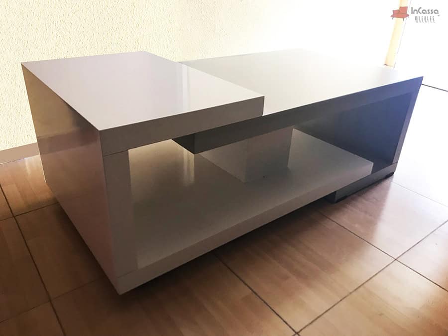 En esta imagen se aprecia el diseño moderno de la mesa ISLANDIA en condiciones de iluminación natural intensa. El reflejo sobre la superficie blanca resalta su terminado en alto brillo, mientras que el contraste entre los volúmenes geométricos blancos y grises mantiene su carácter minimalista y sofisticado.