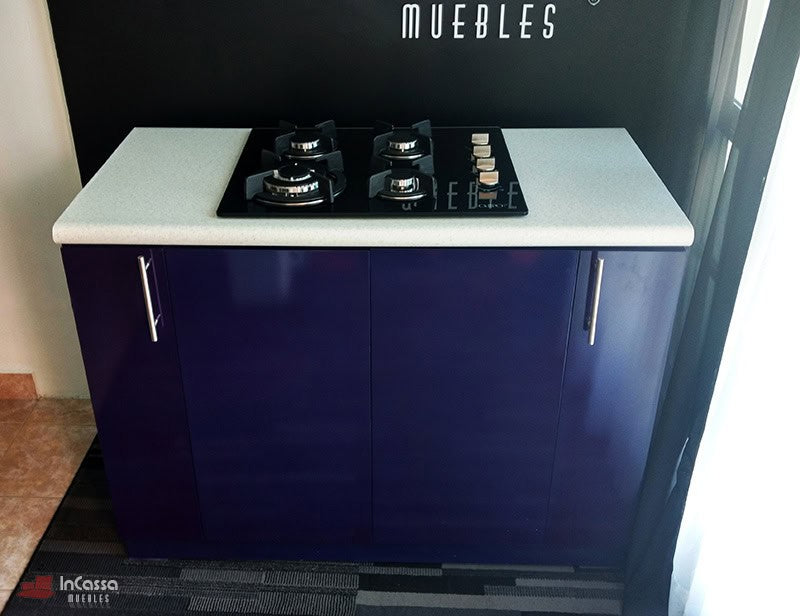 La imagen presenta una vista desde arriba de la Isla LOMBARDIA, mostrando la cubierta de formaica blanca con acabado liso y la parrilla empotrada de cuatro quemadores perfectamente integrada en el diseño compacto del mueble.