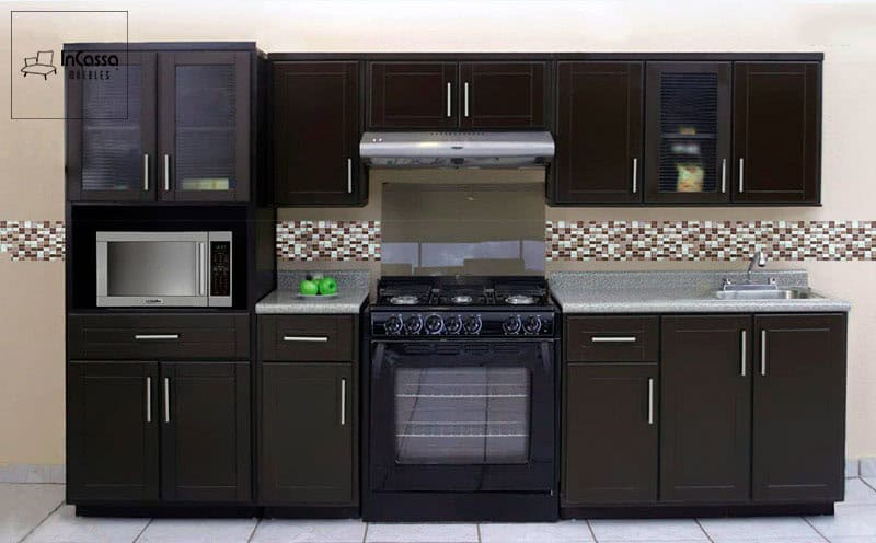 La imagen muestra la Cocina Integral MCALLEN para Estufa en acabado chocolate, vista de frente. Se aprecia su diseño lineal con múltiples módulos superiores e inferiores, cubierta de formaica tono gris y espacio para microondas, estufa y tarja.