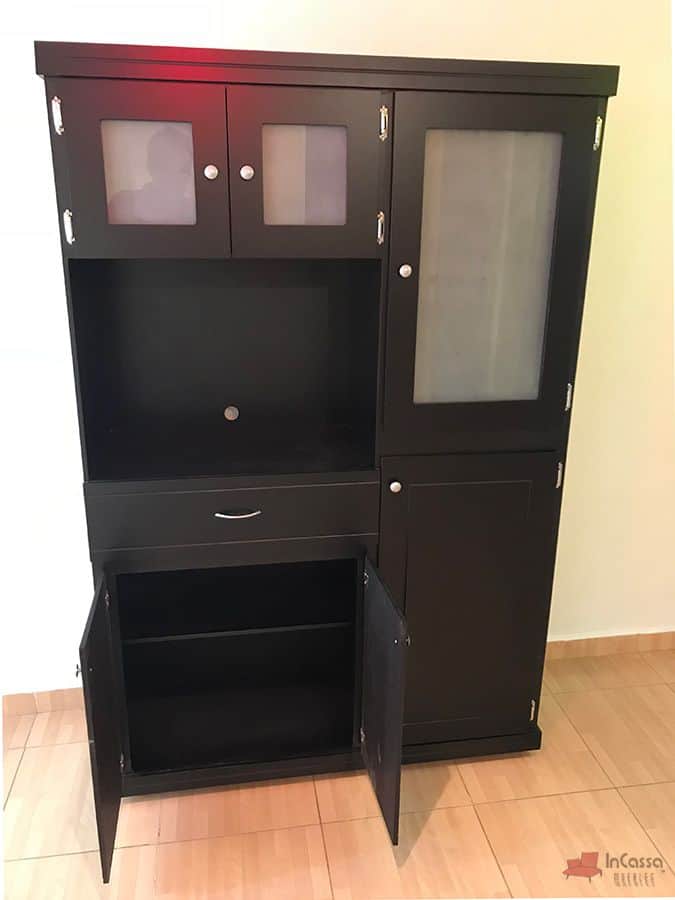 La imagen presenta las puertas inferiores del lado izquierdo completamente abiertas, revelando un compartimento con entrepaño interno ideal para almacenar utensilios grandes. Su diseño en color chocolate y acabado mate armoniza perfectamente con el resto del mueble.