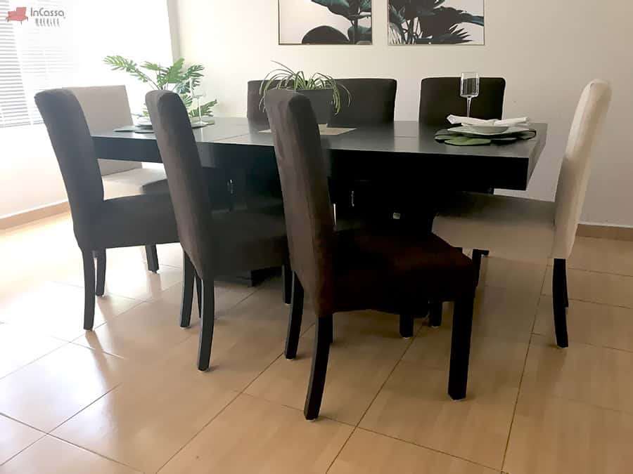La foto muestra el Comedor Modelo RABAT para 8 personas, con mesa en acabado chocolate. Incluye 6 sillas tapizadas en suede color chocolate y 2 en suede tono hueso, creando un contraste elegante y contemporáneo.
