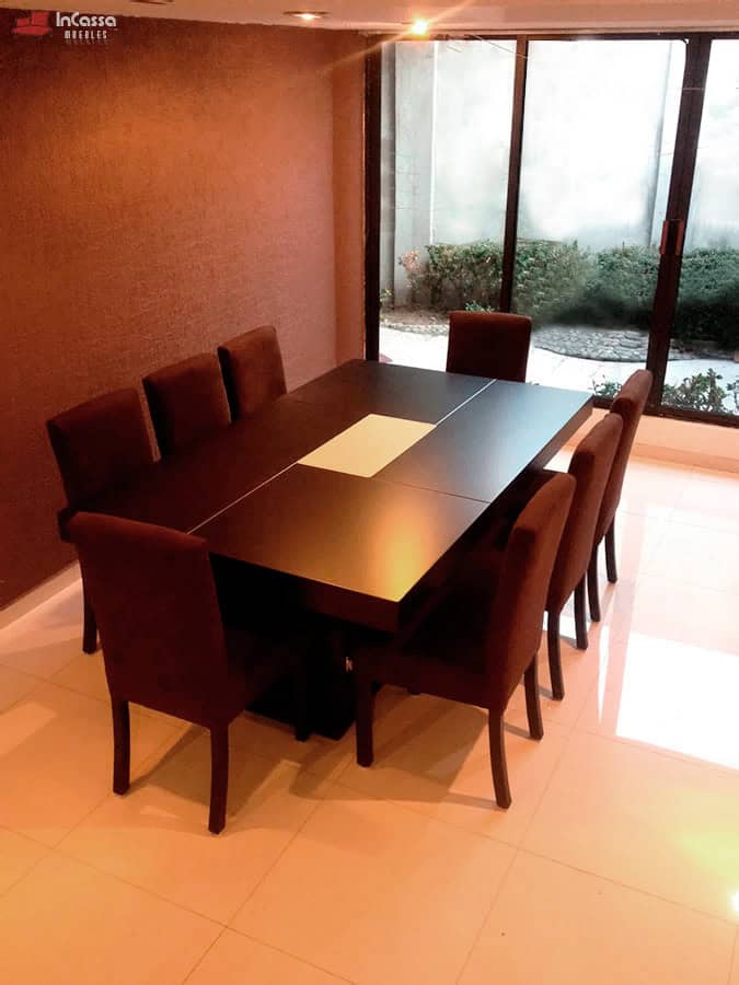 La imagen muestra el Comedor Modelo RABAT para 8 personas, con mesa en tono chocolate y sillas tapizadas en suede color chocolate. Su diseño elegante y sobrio crea un ambiente cálido y moderno ideal para comedores amplios.