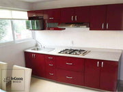 Cocina minimalista diseñada para parrilla empotrable con espacio para microondas, fabricada en color borgoña con cubierta de formica estilo sal y pimienta. La cocina se encuentra instalada en una pared blanca junto a un comedor.