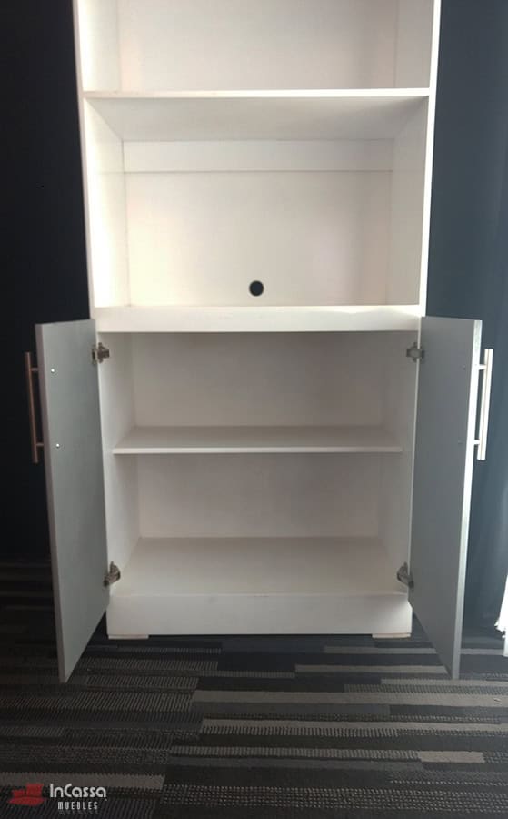 Se presenta un acercamiento frontal al módulo inferior del mueble para hornos Windsor en acabado blanco y silver, con ambas puertas abiertas mostrando un estante interno amplio. Las bisagras metálicas y jaladeras modernas aportan resistencia y estilo, mientras que el diseño facilita el almacenamiento organizado.