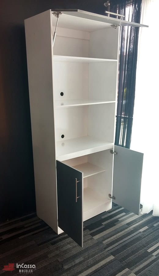 La imagen muestra el mueble para horno Windsor en acabado blanco y silver visto en ángulo lateral, con puerta superior abatible y puertas inferiores abiertas, revelando estantes internos. Incluye perforaciones traseras para cableado y jaladeras metálicas, ideal para organización y funcionalidad moderna.