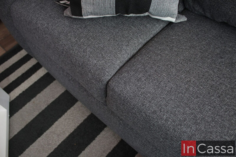 Una toma enfocada en los asientos del love seat, en la que puede apreciarse de manera más cercana la textura de su tapiz en lino color mouse. También queda a la vista parte de la base del módulo el cuál comparte el mismo tapiz que los asientos.