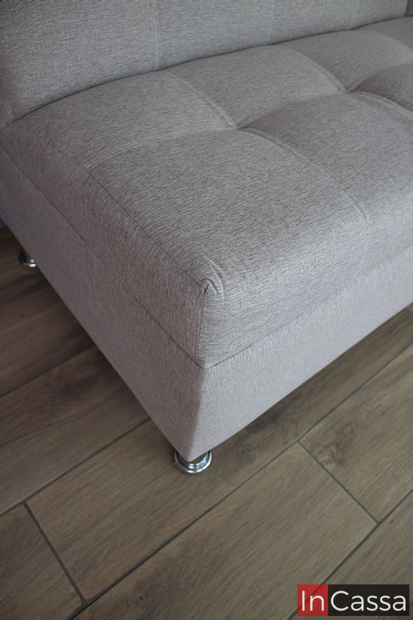 Una mejor vista de uno de los asientos, en la que además de poder apreciar mucho mejor la textura del tapizado en lino color greige, también podemos observar detalles como las costuras y el acabado capitoneado en el mueble.