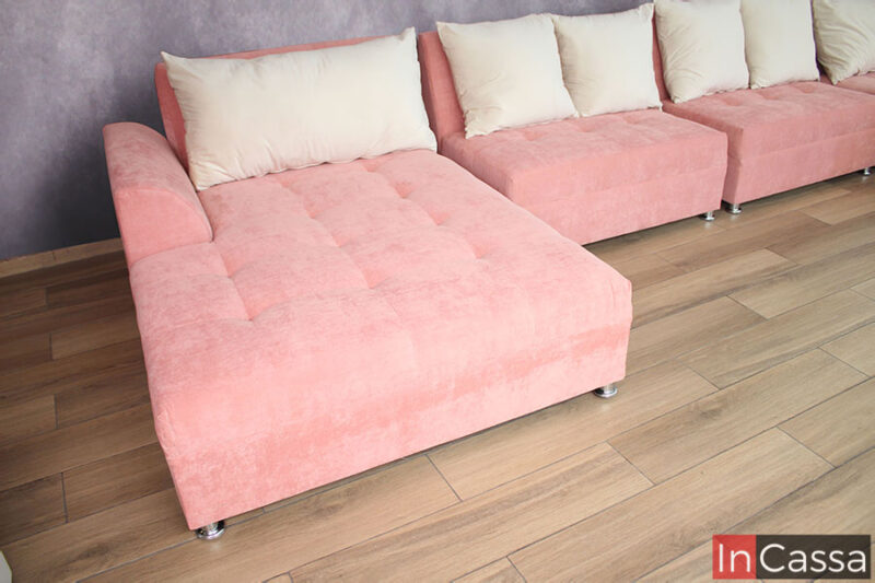Un mayor enfoque al chaise long izquierdo en tapiz suede rosa (viendo la sala de frente), junto a ambos love seat del mismo color y los cojines de suede hueso que decoran cada modulo.