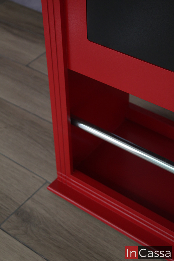 Una mejor toma de la parte inferior de la cantina, en la que destaca la barra posa pies metálica instalada en el mueble. También podemos ver parte de uno de los parches decorativos de color negro, así como apreciar el color rojo de toda la barra cantina.