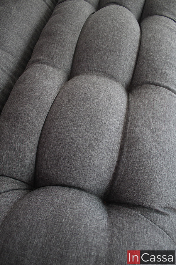 La foto nos enseña una toma cercana del asiento del sofá cama, en la que se puede apreciar de mejor manera los detalles capitoneados del tapizado así como la textura de la tela lino mouse.