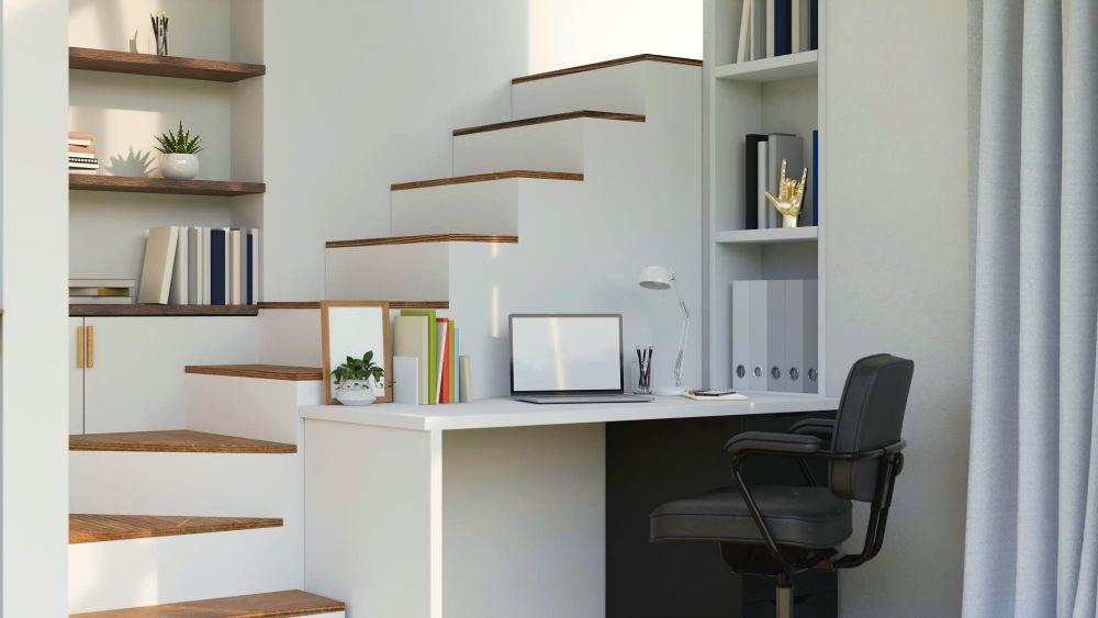un escritorio con librero instalado en un pequeño espacio junto a una escalera