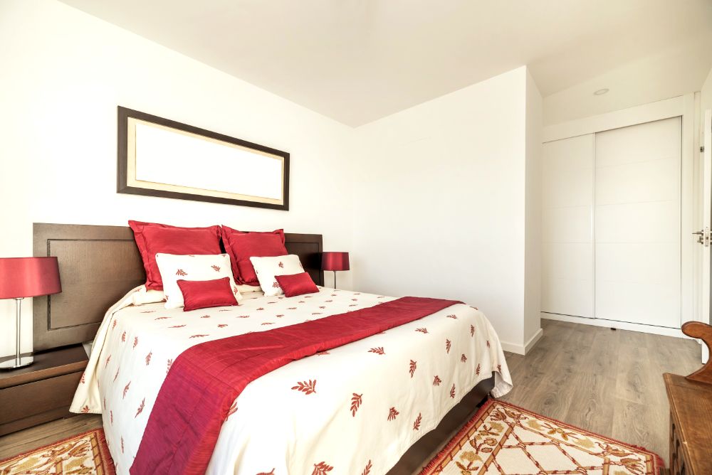 Dormitorio moderno con cama queen size blanca y roja, lámparas a juego y decoración minimalista.