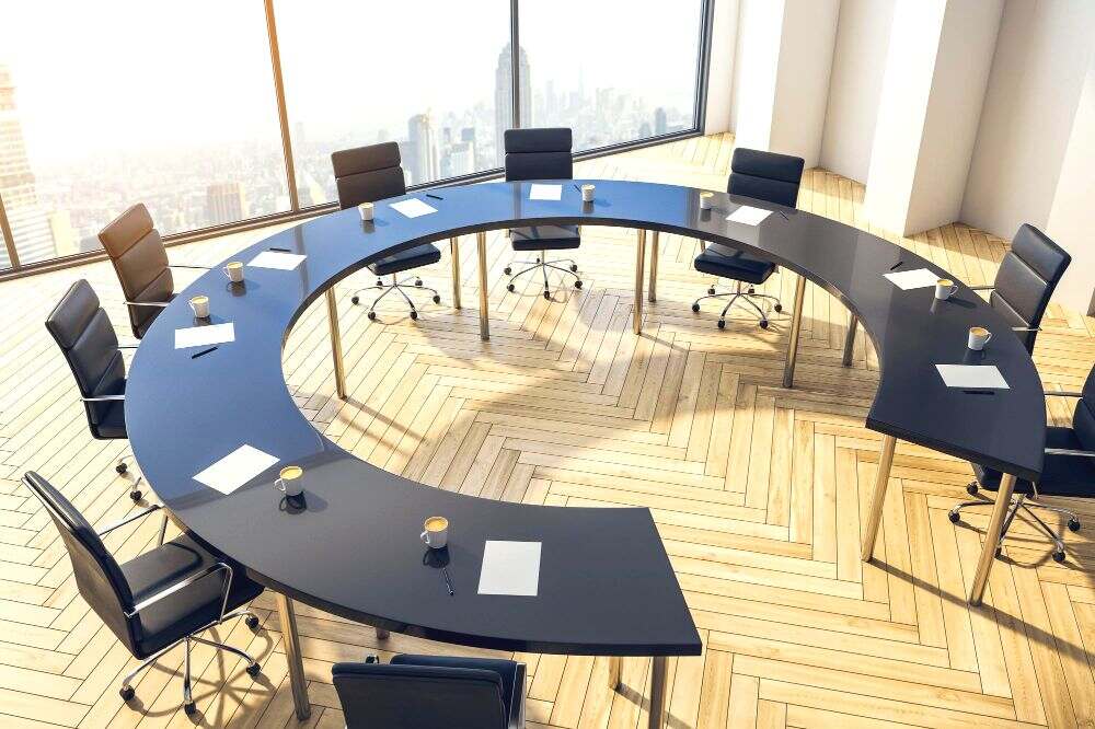 una mesa negra con forma de herradura en una gran oficina