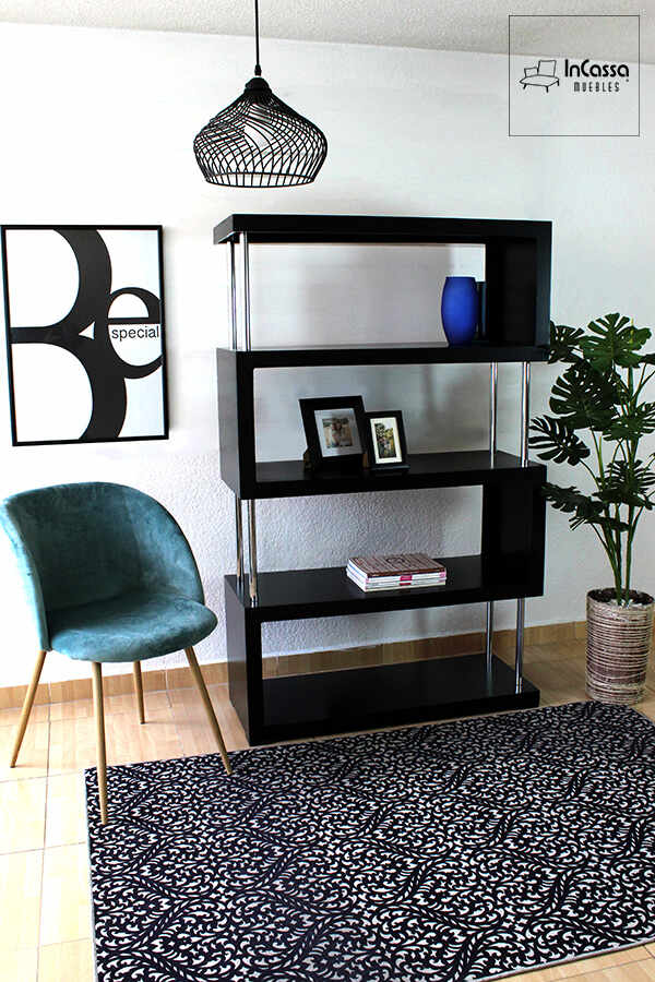 Moderno librero de color negro fabricado de MDF chileno con algunos tubos metálicos para complementar la estructura. El librero se encuentra instalado en una estancia con paredes blancas y piso de madera.